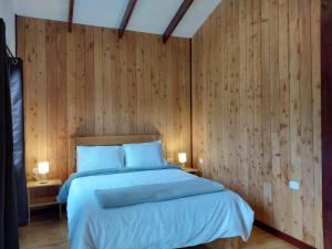 Copey的住宿－Curuba Lodge，一间卧室配有一张带木墙的大床