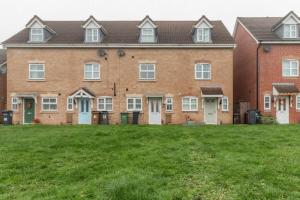 a large brick building with a green lawn in front of it at Lolite Homes - 4 Bed Perfect for NEC Genting Arena Resort World & Airport - Serviced Hawk Home in Birmingham