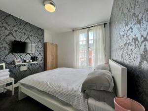 a bedroom with a bed and a tv on a wall at Oxford Street Stays in Southampton
