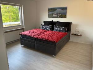 1 dormitorio con 1 cama grande con manta roja en Ferienwohnung Zum Wildpark, en Lago Éder
