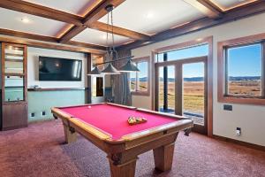 uma mesa de bilhar num quarto com uma televisão e janelas em Raz Hideaway 7BR Ranch with Panoramic Mountain Views em Sturgis