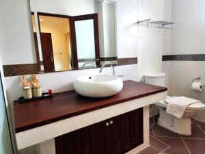 a bathroom with a sink with a mirror and a toilet at The Peaberry Boutique Hotel in Chiang Mai
