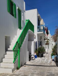 a group of white buildings with green doors and stairs at Rania's Home in Mikonos