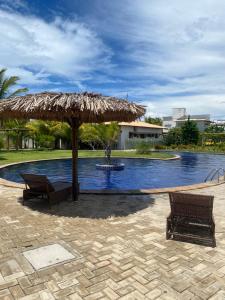 a large pool with a straw umbrella and two benches at Santo Mar Em São Miguel do gostoso in Touros +7 photos