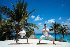 two men doing yoga on the beach at Paradisus Cancun All Inclusive in Cancún