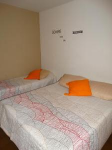 Duas camas com almofadas laranja num quarto em Departamento Benissa en San Juan em San Juan