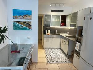 a kitchen with a refrigerator and a table in it at Garden apt at the Marina Herzliya in Herzliyya B