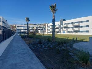 un gran edificio con palmeras y una acera en Valleniza ViaCelere 2 dormitorios, en Vélez-Málaga