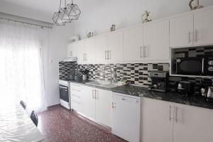 een keuken met witte kasten, een wastafel en een magnetron bij casa bianca in Nea Kalikratia