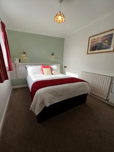 a bedroom with a large bed with red and white sheets at Queenswood Hotel in Weston-super-Mare
