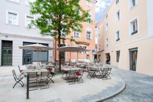 een groep tafels en stoelen met parasols op een binnenplaats bij Goldenes Schiff in Passau