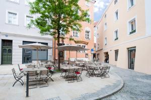 a group of tables and chairs with umbrellas in a courtyard at Goldenes Schiff in Passau