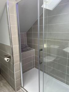 a shower with a glass door in a bathroom at Luxury Studio Loft with Car Charging Point in Frizington