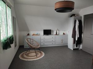 a room with a chair and a dresser with a television at Chambre à louer proche circuit in Teloché