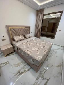 a bedroom with a bed with marble floors and a window at apartment de luxe hay almatar 2 in Nador +3 photos