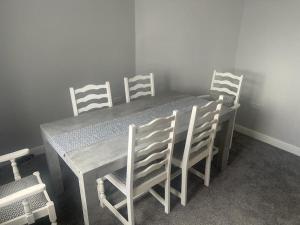 a dining room table with four white chairs around it at House near city centre in Leicester