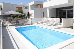basen z krzesłami i parasolem obok domu w obiekcie Apartment Villa Lumada with Pool w Novalji
