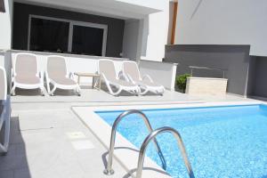 basen z białymi krzesłami i basen w obiekcie Apartment Villa Lumada with Pool w Novalji