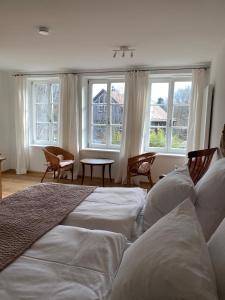 a bedroom with a bed with white sheets and windows at Alte Mühle Maising in Pöcking