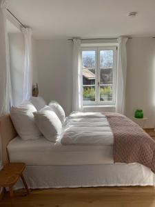 una camera da letto con un letto con cuscini bianchi e una finestra di Alte Mühle Maising a Pöcking