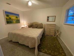 a bedroom with a bed and a dresser and a window at Vintage Vero Bungalo II in Vero Beach
