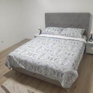 a bed with a gray and white comforter and pillows at Apartman Family in Sarajevo