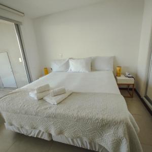 1 cama blanca grande con 2 toallas en Dos Orillas - Apartamento 302, en Colonia del Sacramento