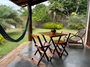 una mesa y sillas en un porche con hamaca en Casa nos Algodoes, en Maraú