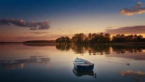 a boat sitting in the water at sunset at Domek nad jeziorem Drężno noclegi wynajem+sauna 