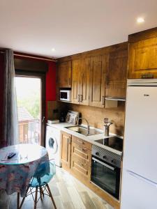 a kitchen with wooden cabinets and a table and a refrigerator at Apartamentos DELUXE Con Jacuzzi o Chimenea LOVE FOR TWO in Collado Mediano