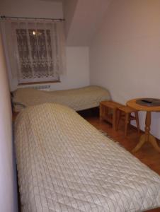 a bedroom with two beds and a table and a window at Gospoda Rycerska in Szydłów