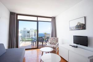 Apartamentos Don Quijote في كالا راتخادا: غرفة معيشة مع أريكة وتلفزيون