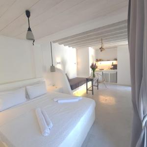 a white bedroom with a white bed with two towels on it at Bella Alba in Kalafatis