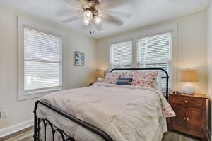 a bedroom with a bed with a ceiling fan and two windows at Beautiful Stylish Home in Avondale Jacksonville in Jacksonville