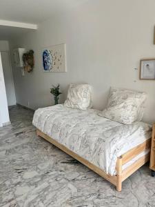 uma cama num quarto branco com uma estrutura de cama em Studio cosy avec terrasse sur la plage em La Seyne-sur-Mer