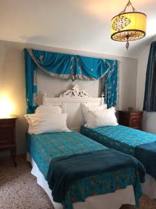 Duas camas num quarto com cortinas azuis e um lustre em Holiday Home Carina em Dolceacqua