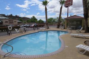 a swimming pool at a resort with chairs and palm trees at America's Best Inn & Suites Saint George in St. George