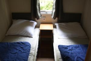 two beds in a small room with a table at Chalet with large veranda 6p centrally located in National Park, Swimming pool in Wateren