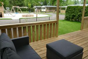 a wooden deck with a bench and a playground at Chalet with large veranda 6p centrally located in National Park, Swimming pool in Wateren