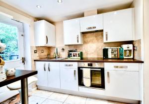 a white kitchen with white cabinets and a table at Cosy Garden Flat, Private Roofed Hot Tub & Four Poster Bed in York