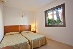 sypialnia z dwoma łóżkami i oknem w obiekcie Apartamentos Don Quijote w Cala Ratjada +37 zdjęć