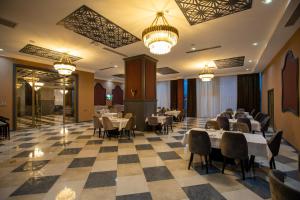 a dining room with tables and chairs and chandeliers at Volga Hotel Baku in Baku