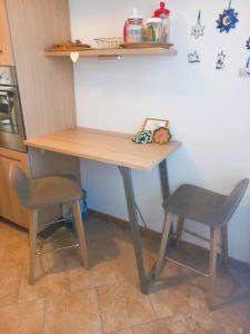 uma mesa de madeira e duas cadeiras numa cozinha em Casa Cocoon - holiday home em Brindisi