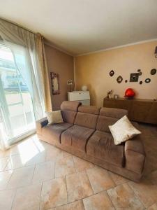 uma sala de estar com um sofá castanho em frente a uma janela em Casa Cocoon - holiday home em Brindisi