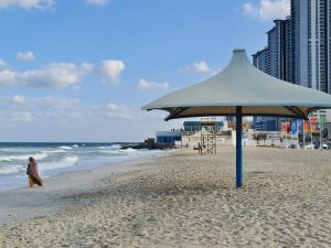 a person walking on the beach under an umbrella at Beachfront Holiday Homes in Ajman 