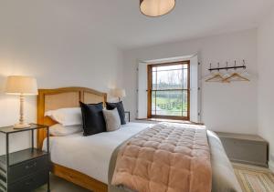 a bedroom with a large bed and a window at Higher Treliver Farmhouse in Saint Wenn