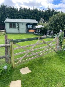 a wooden fence in front of a house at Cosy 2 BR cabin on coast private hot tub ' Driftwood ' in Stolford