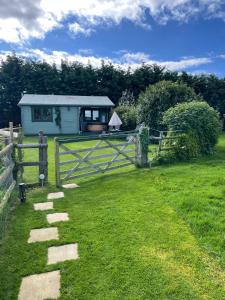 a house in a field with a fence at Cosy 2 BR cabin on coast private hot tub ' Driftwood ' in Stolford