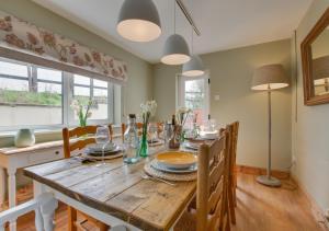 a dining room with a wooden table and chairs at Higher Treliver Farmhouse Piggery in Saint Wenn