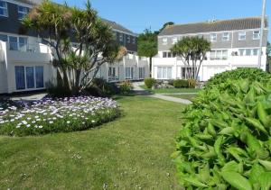 a yard with flowers and palm trees and buildings at Blue Horizon in St Ives